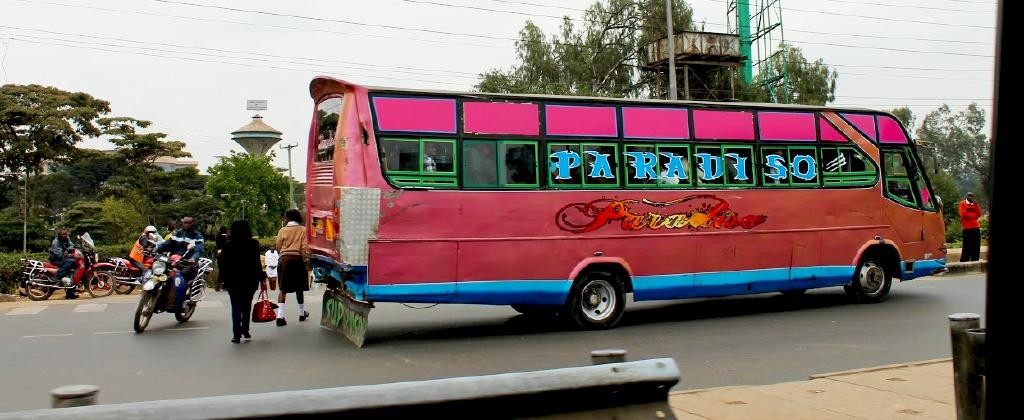 A picture of a bus, pedestrians and a motorcycle taxi in Nairobi, Kenya